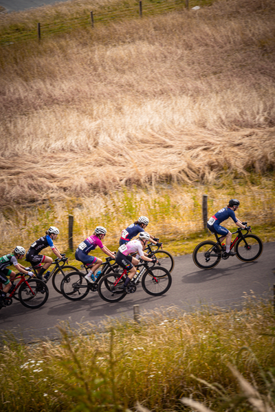 A group of cyclists race in a competition and they are sponsored by Dames Elite ZC.