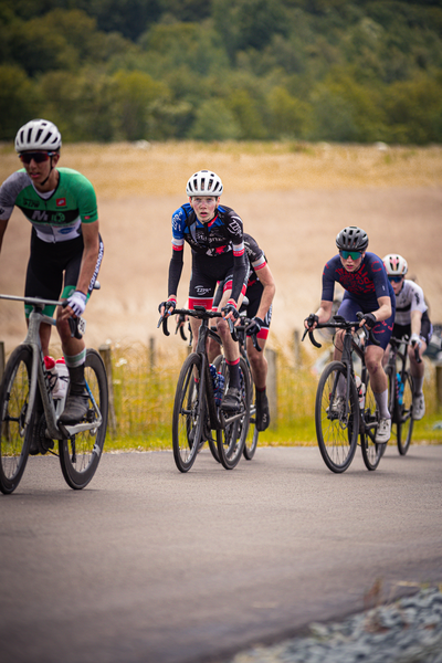 Three cyclists racing on a road with one wearing the number 2.