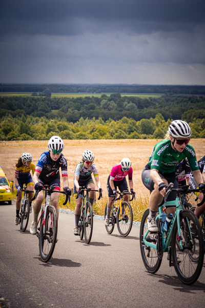 A group of cyclists racing on a road, with each cyclist wearing different colored jerseys.