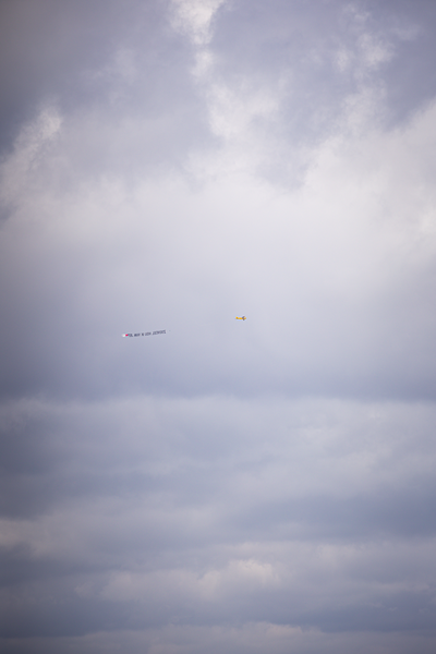 A group of birds fly next to a yellow kite in the sky.