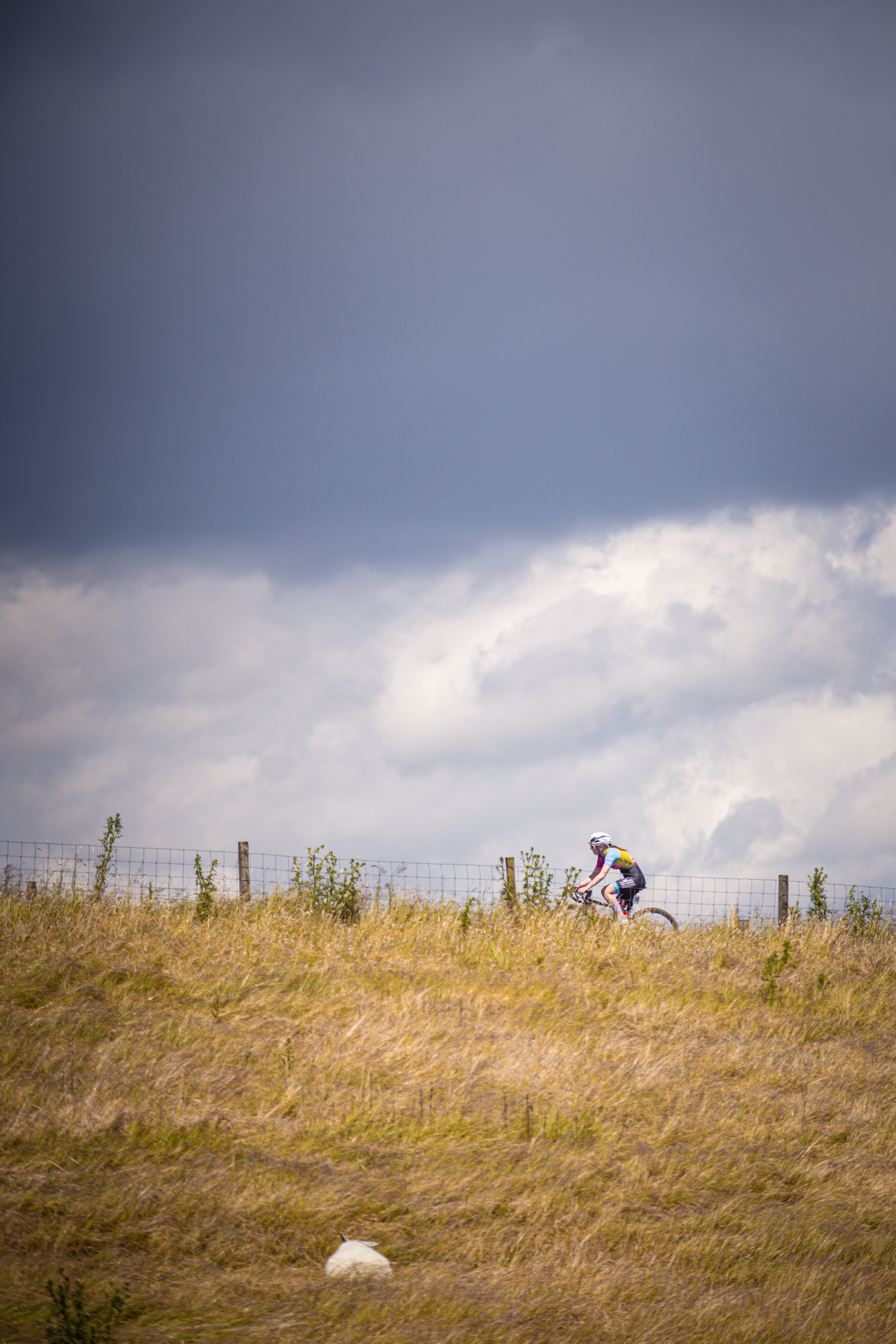 A person wearing a white hat rides a bike on a grassy hill.