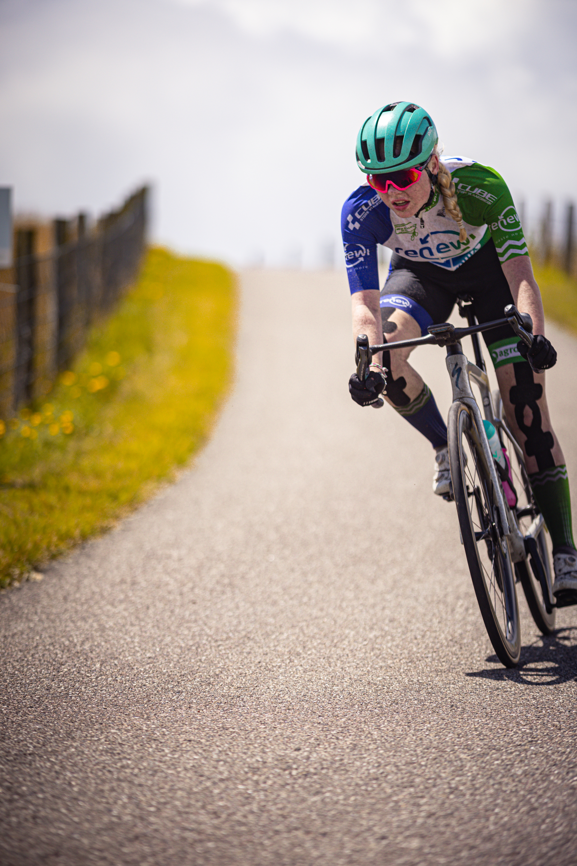 A young woman wearing a blue helmet is racing her bicycle.