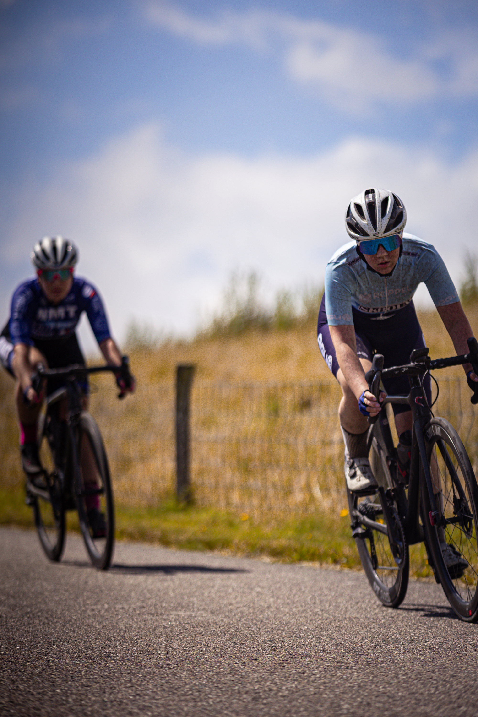 Two female cyclists on a road with the lead cyclist wearing the number 1 on her shirt.