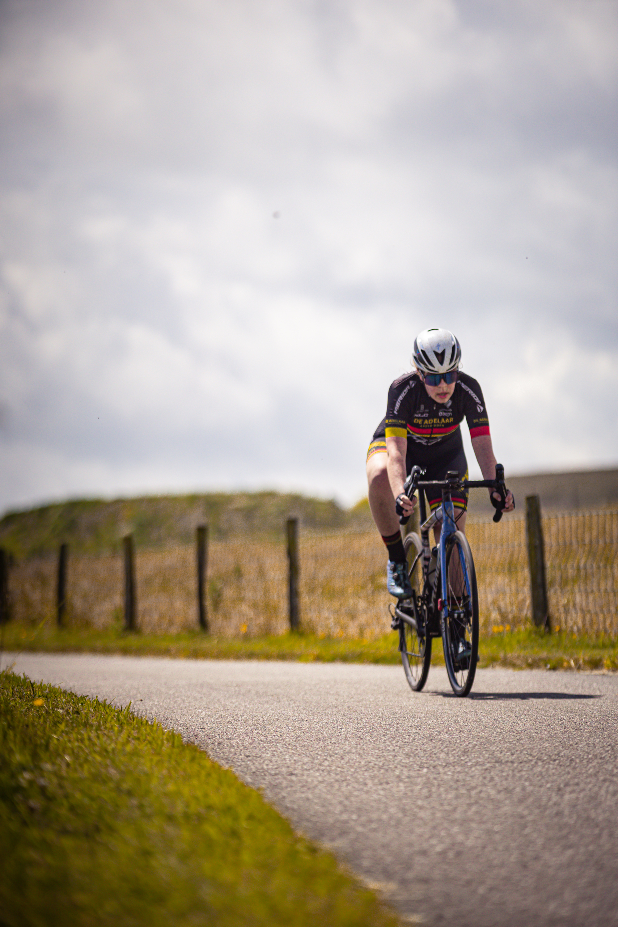 A woman wearing a helmet rides her bike on a road.