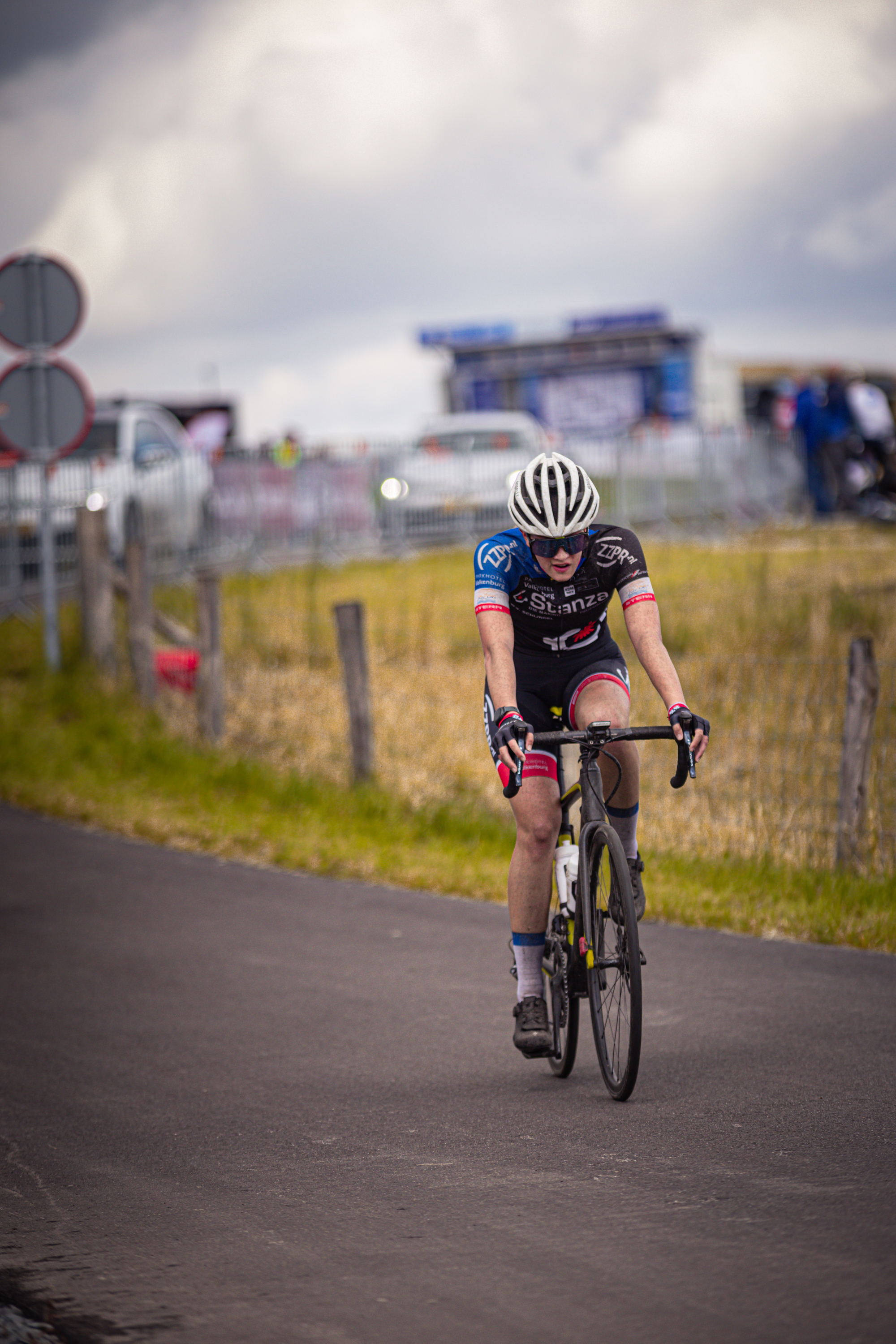 A cyclist wearing the number 10 and a blue helmet goes down the road.