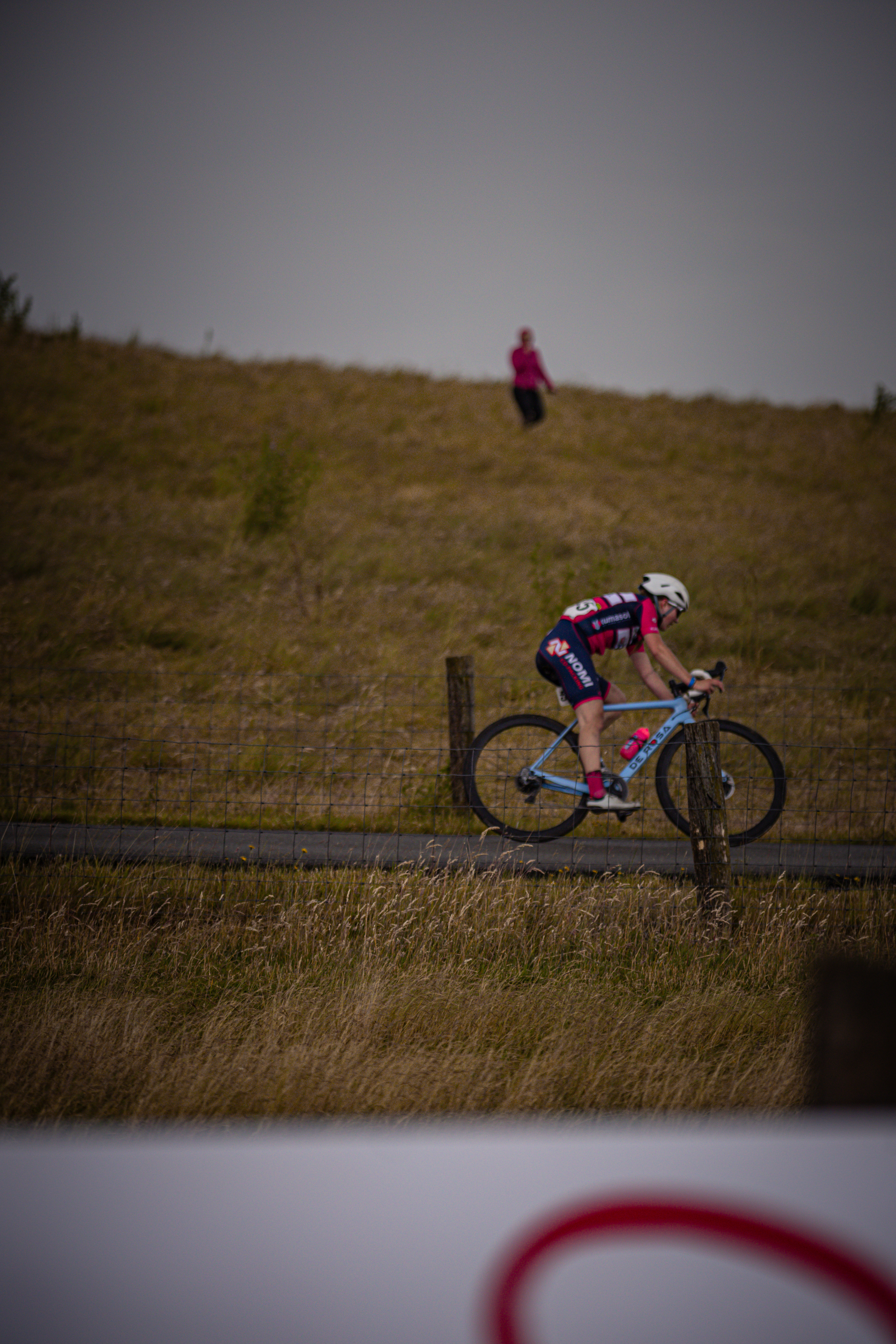 A cyclist wearing a white helmet is riding her bike down a hill.