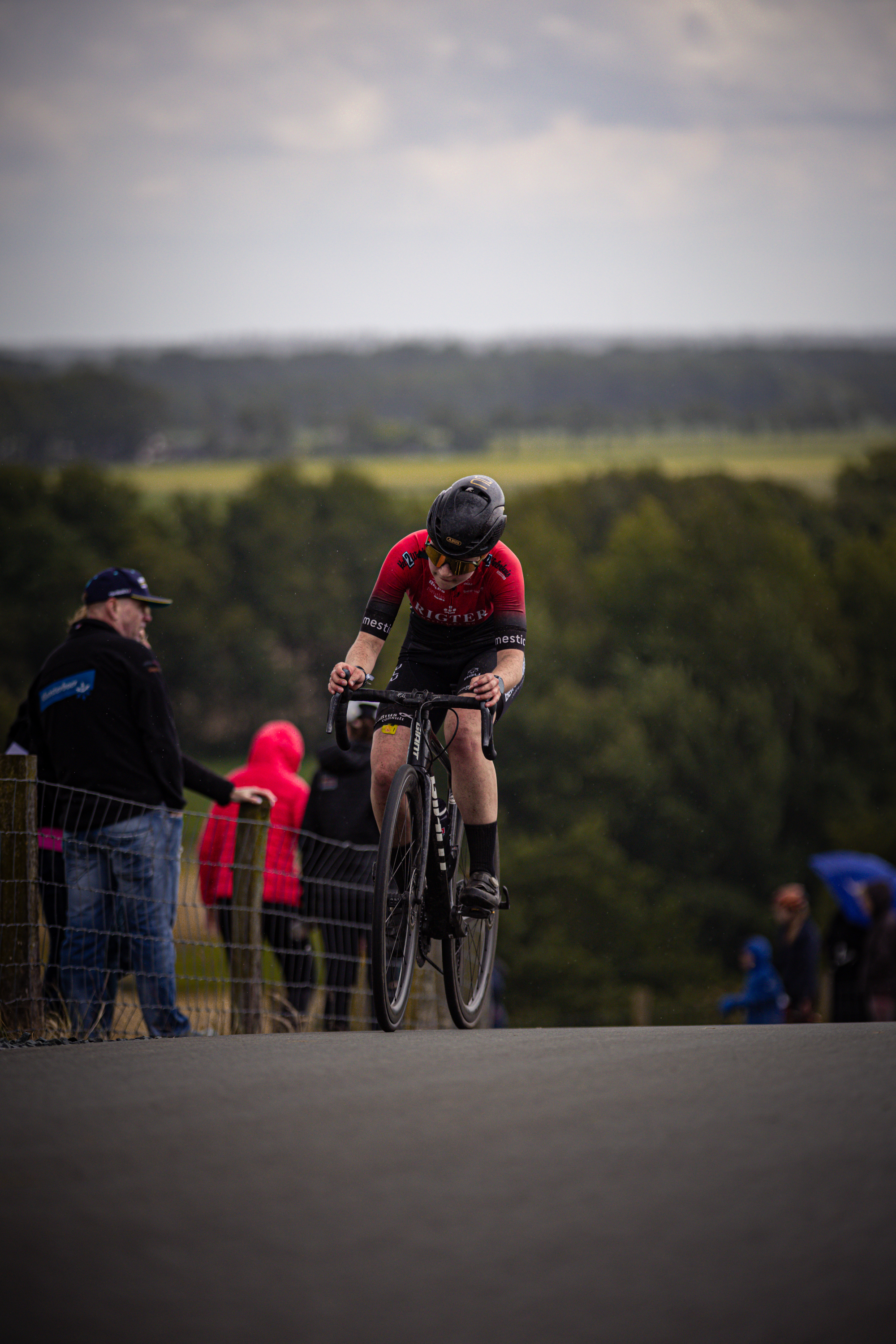 A bicycle racer is riding on a road during the Nederlands Kampioenschap Wielrennen event.