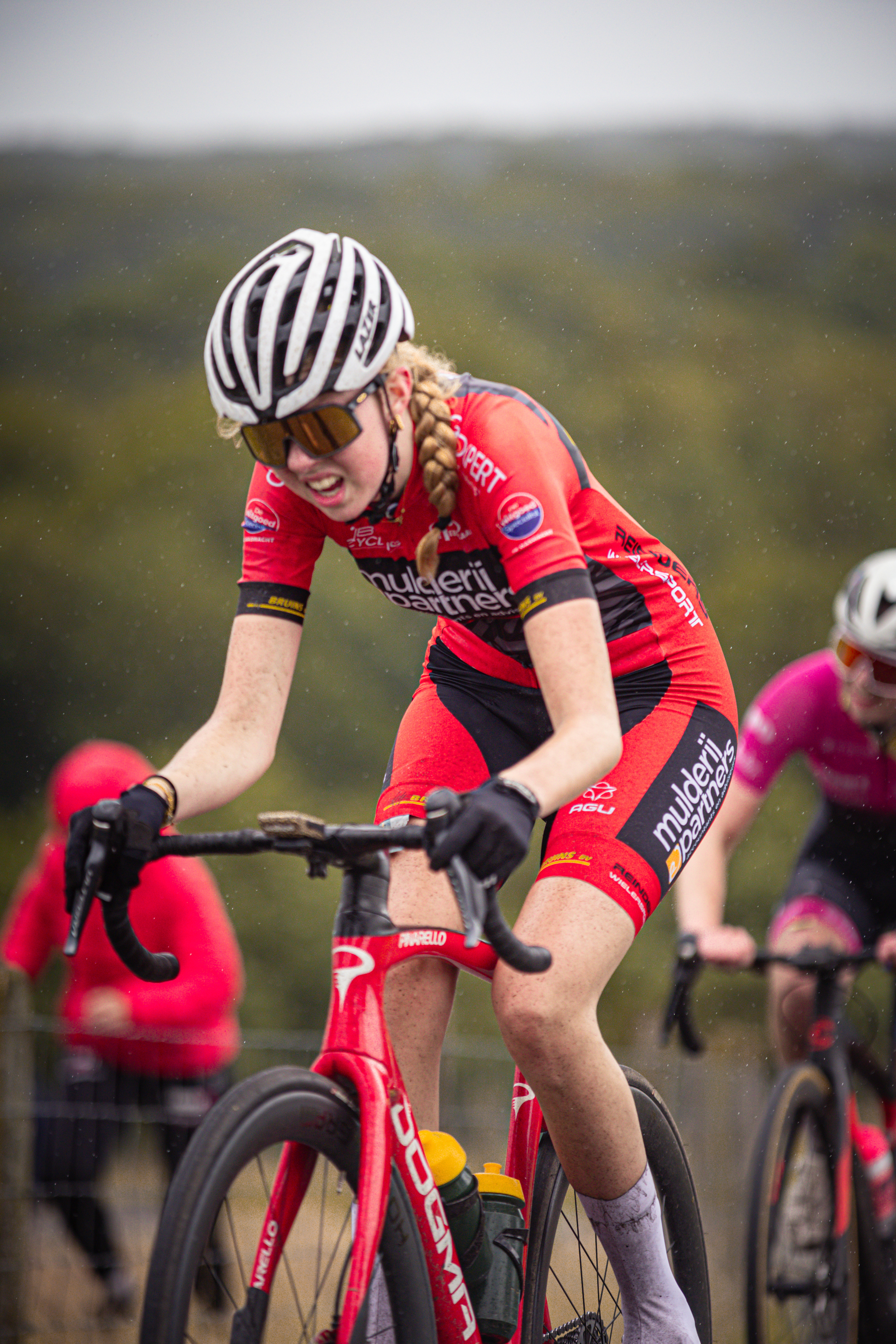 A woman wearing a red and black cycling outfit at the Nederlands Kampioenschap.