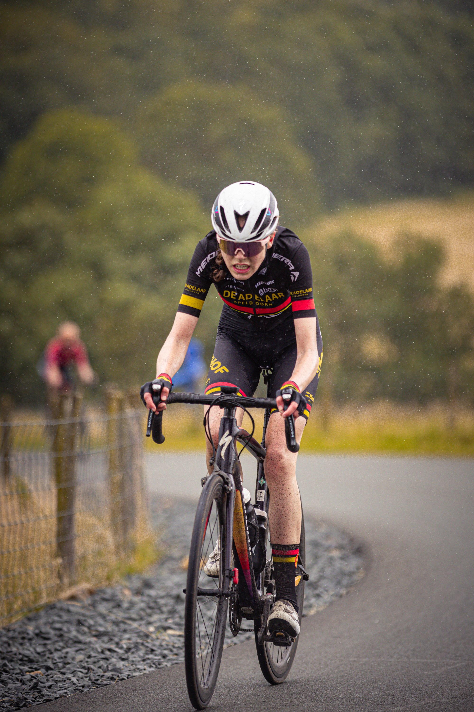 The cyclist is wearing a black shirt with red writing on it.