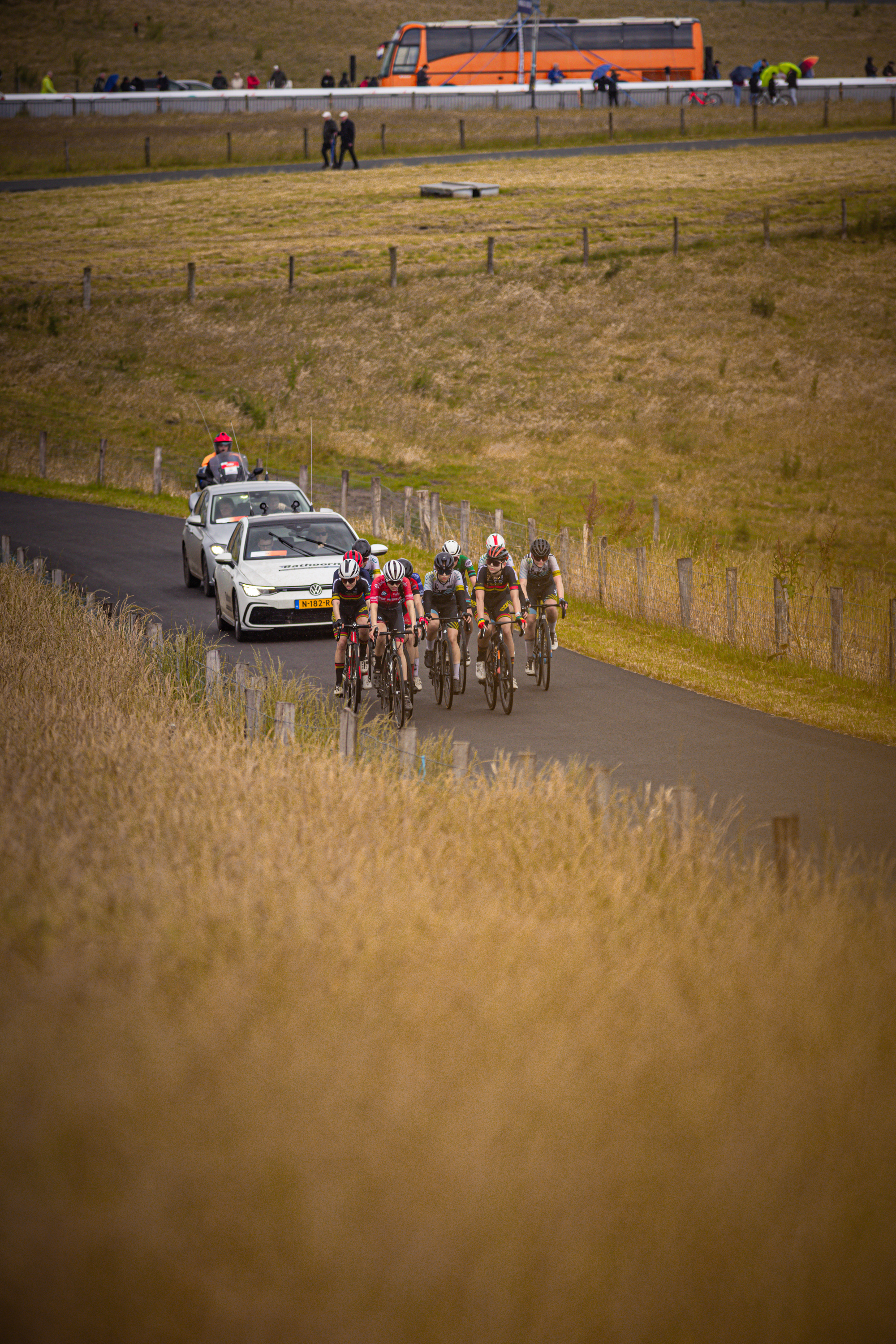 A group of cyclists race on a rural road during the Nederlands Kampioenschap.