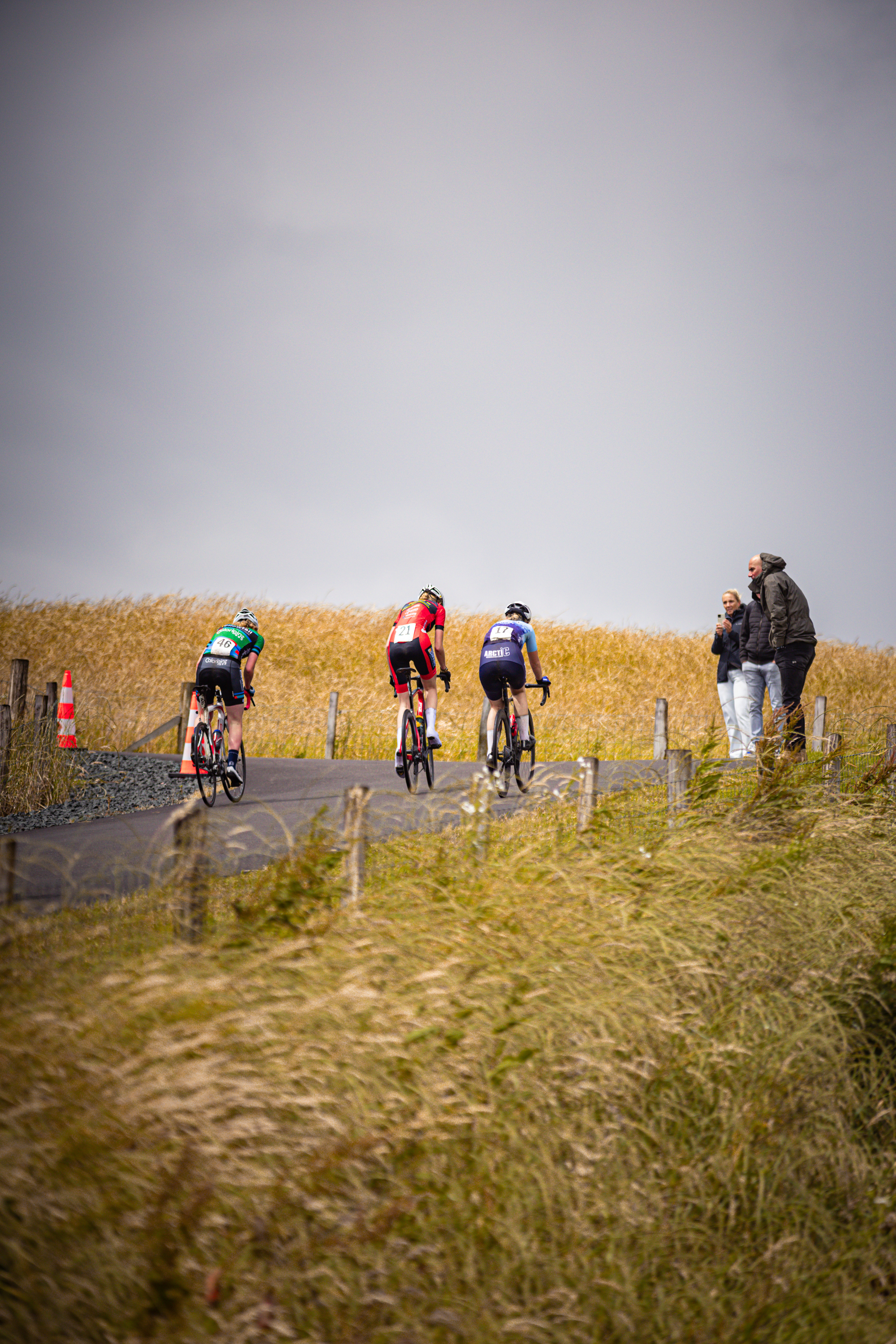 Nederlands Kampioenschap, 2024 - Wielrennen in a field with three cyclists and spectators.