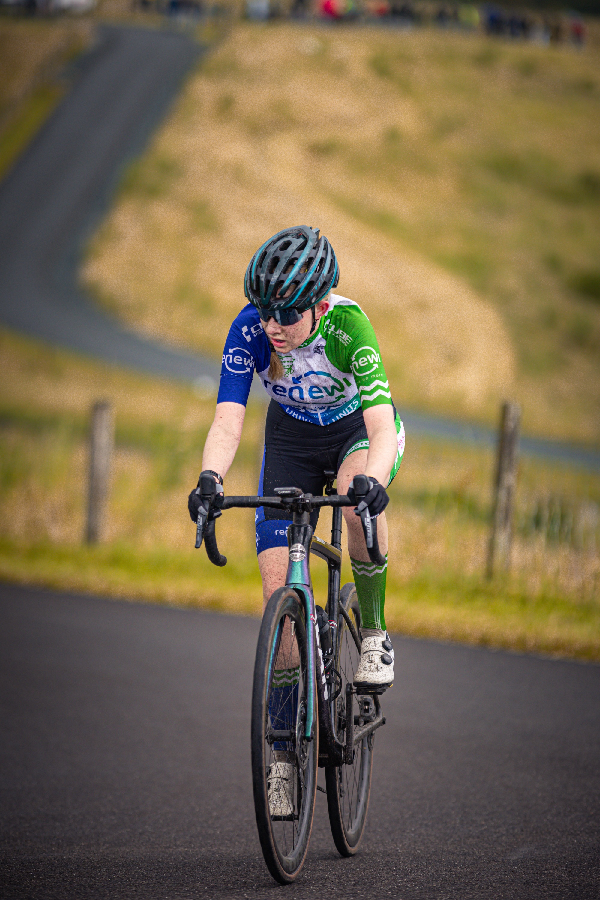 A young cyclist is in the middle of a race, looking back with determination.