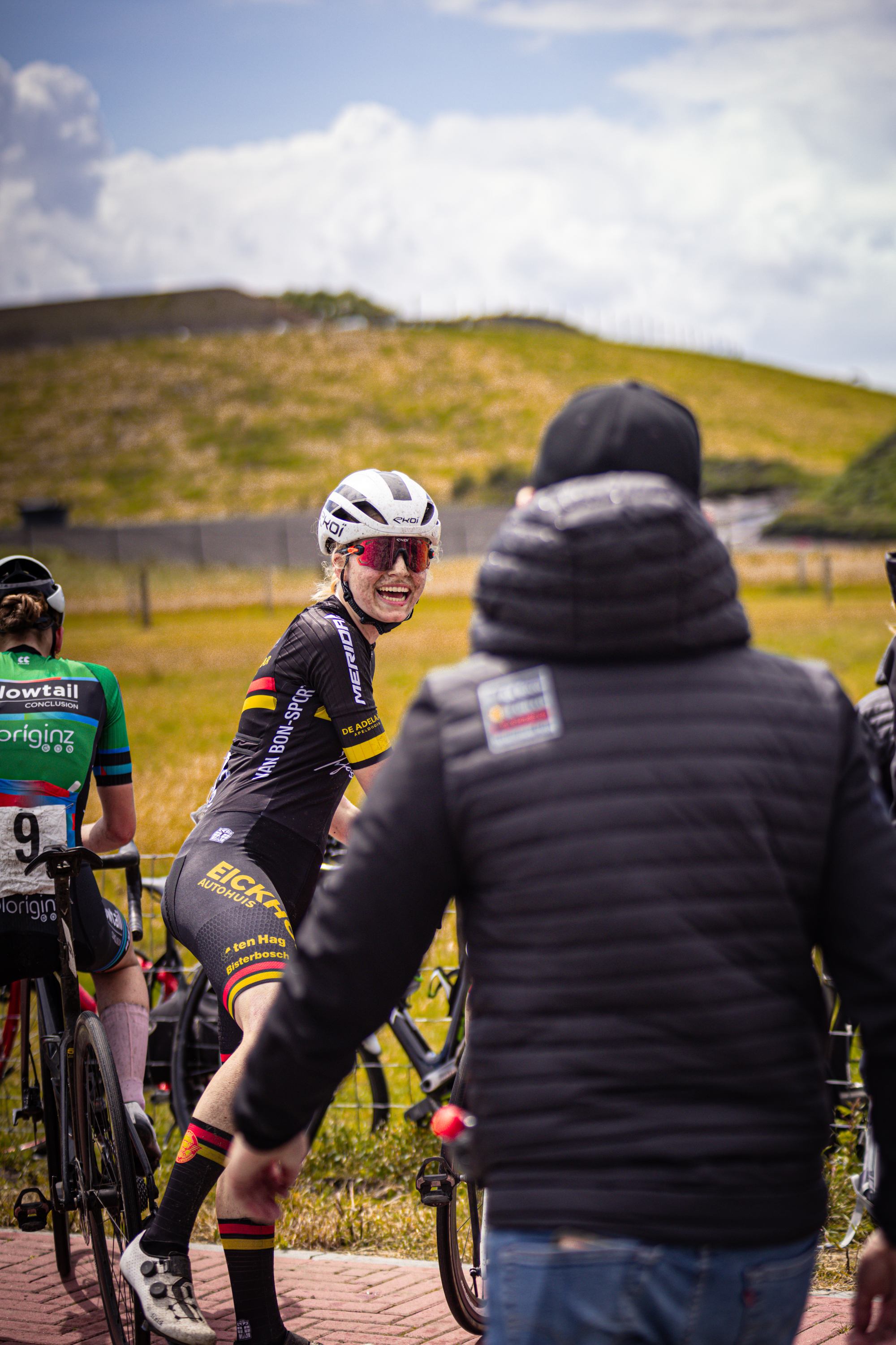 A group of cyclists, one wearing the number 12 jersey, are riding on a path.