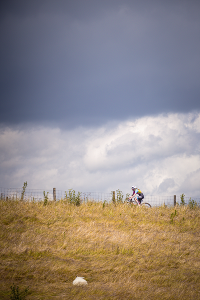 A person wearing a white hat rides a bike on a grassy hill.