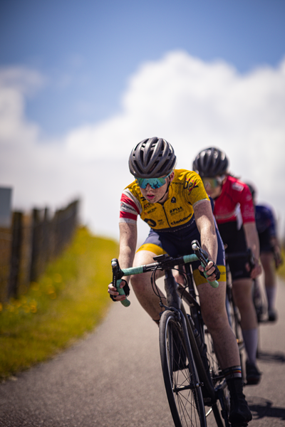 A cyclist wearing a yellow shirt with the number 9 on it is riding a bicycle.