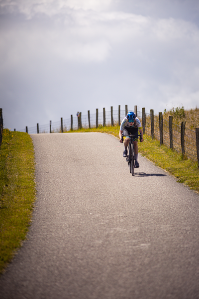 A cyclist wearing a blue helmet rides her bike on the road.