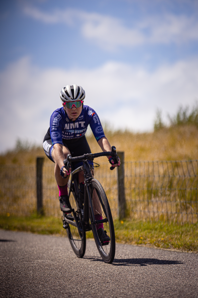 A cyclist wearing a white and blue shirt is riding on the road.