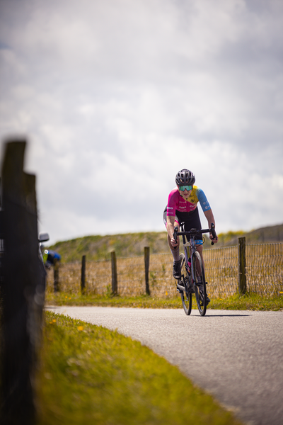 De fietsreder in de rode en blauwe truiers rijdt in het Nederlands Kampioenschap op weg naar een winst.