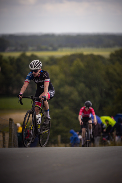 Two cyclists are riding on a road in the Netherlands during the Kampioenschap Wielrennen.