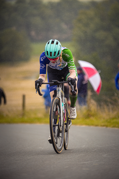 A cyclist with a green helmet is wearing a blue and white jersey.