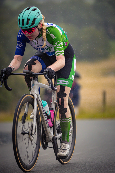 A cyclist is wearing a helmet and a green jersey with the word "Nederlands" on it.