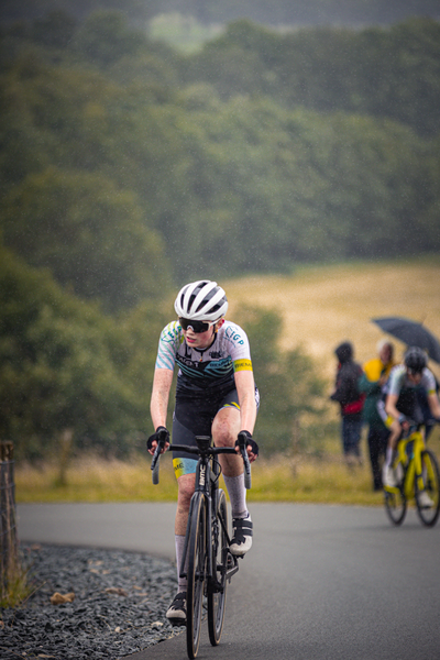 Two cyclists riding in the rain. One of them has the number 5 on their back.