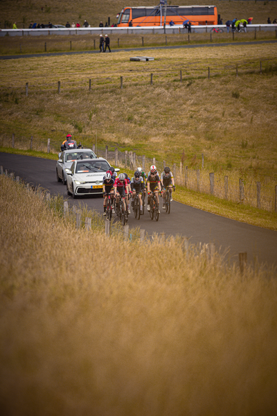 A group of cyclists race on a rural road during the Nederlands Kampioenschap.