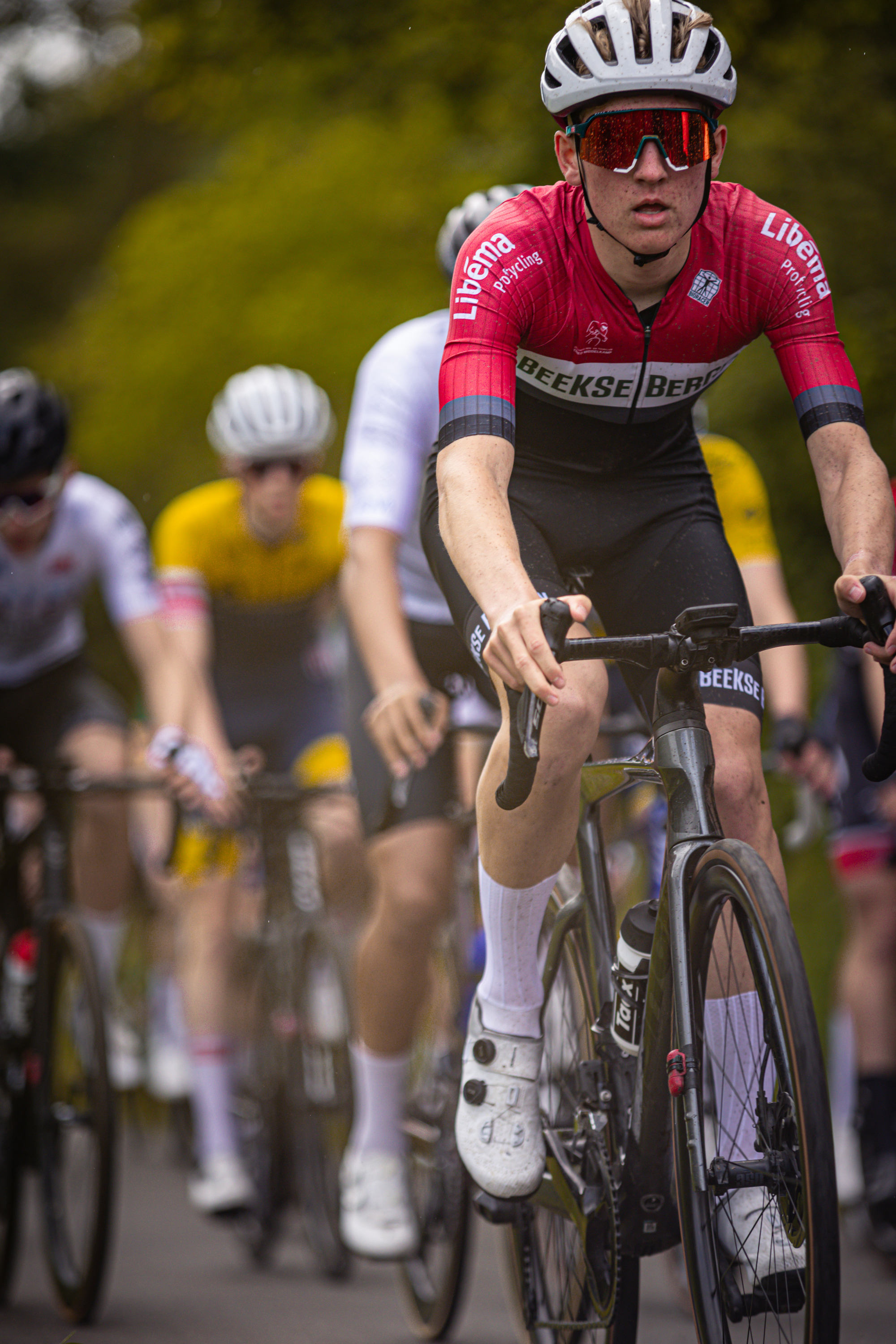 A bicycle racer with the words "Kampioenschap" and a logo on his uniform, riding on a track.