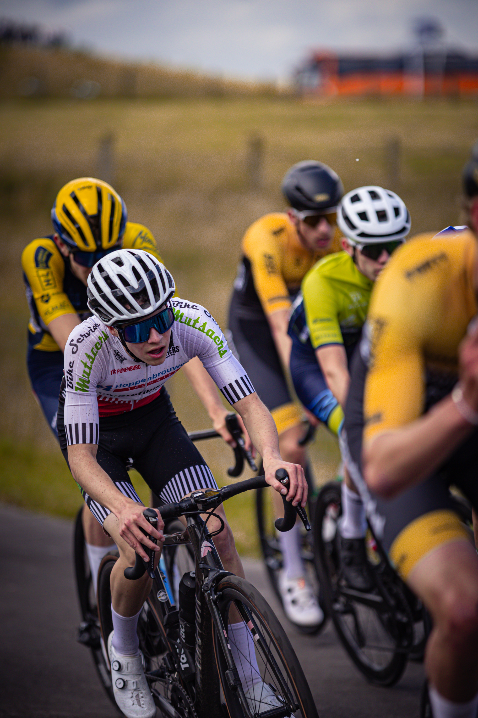 Three cyclists on a race track with the front cyclist wearing number 21.