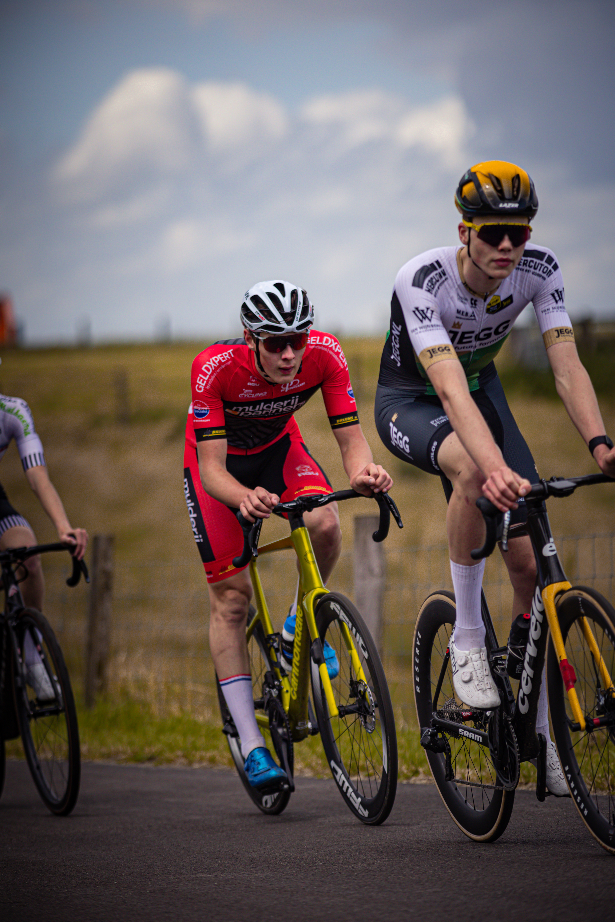 Junioren Mannen bicycle racers are riding through a field.