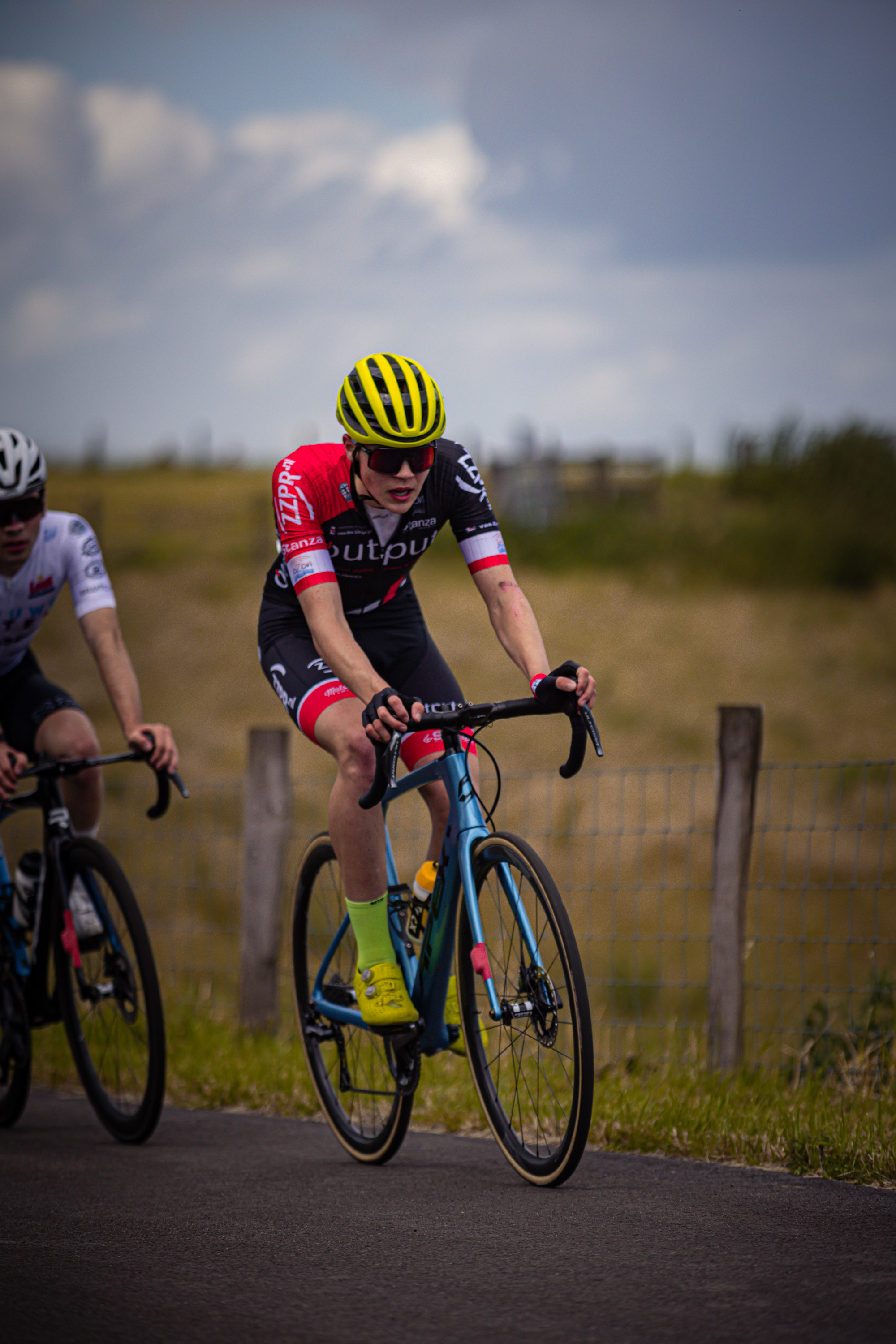 Two cyclists are in a race with one wearing a red and black jersey.