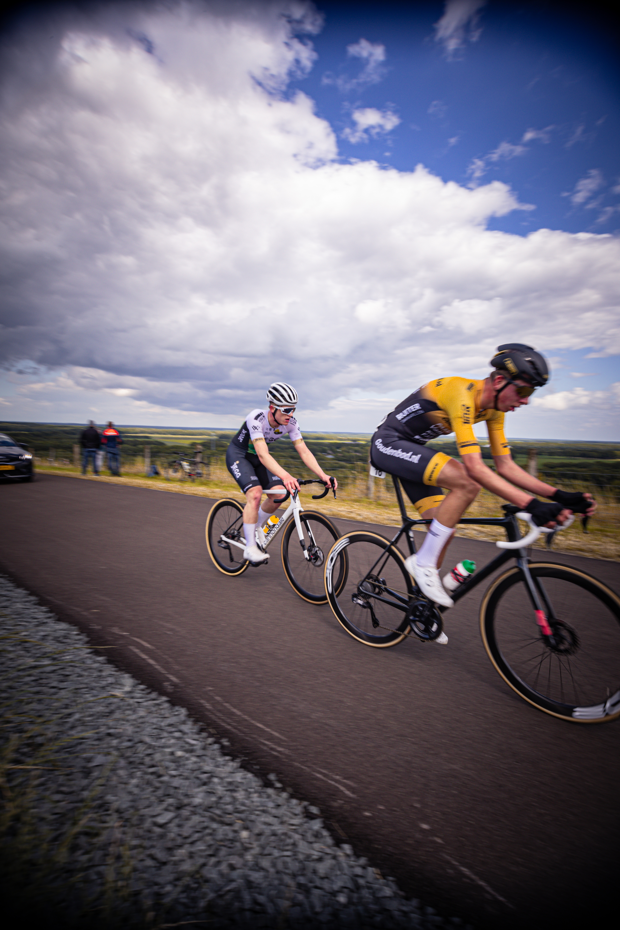 Two cyclists compete in a race under an overcast sky.