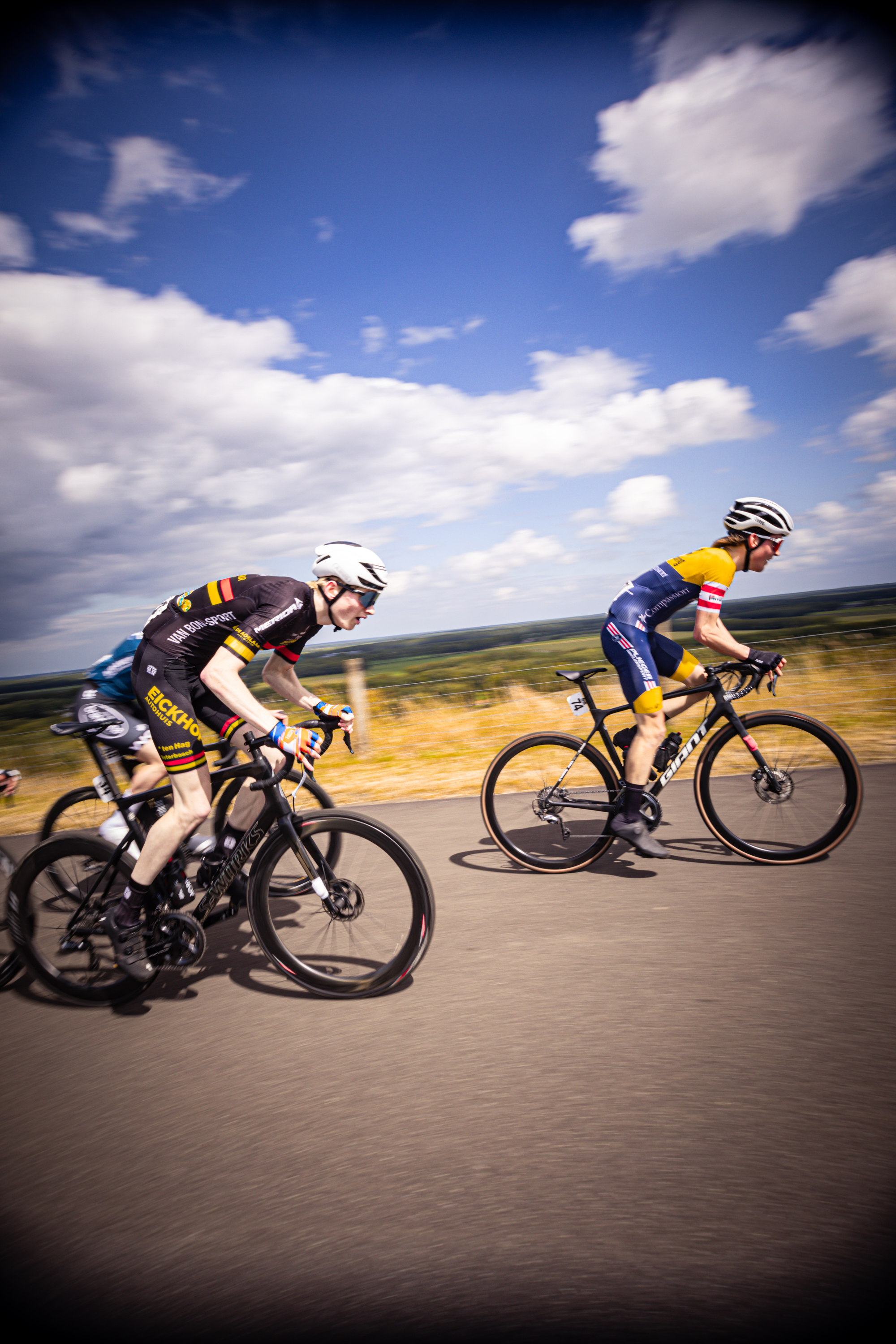 Two young men are riding bicycles in a grassy field.