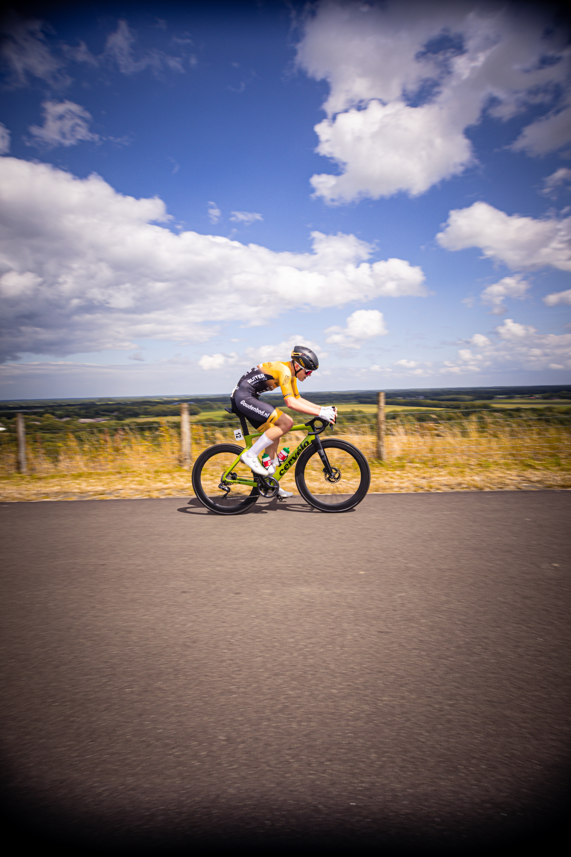 A man is riding a bike on the road with a white number 1 on his back.