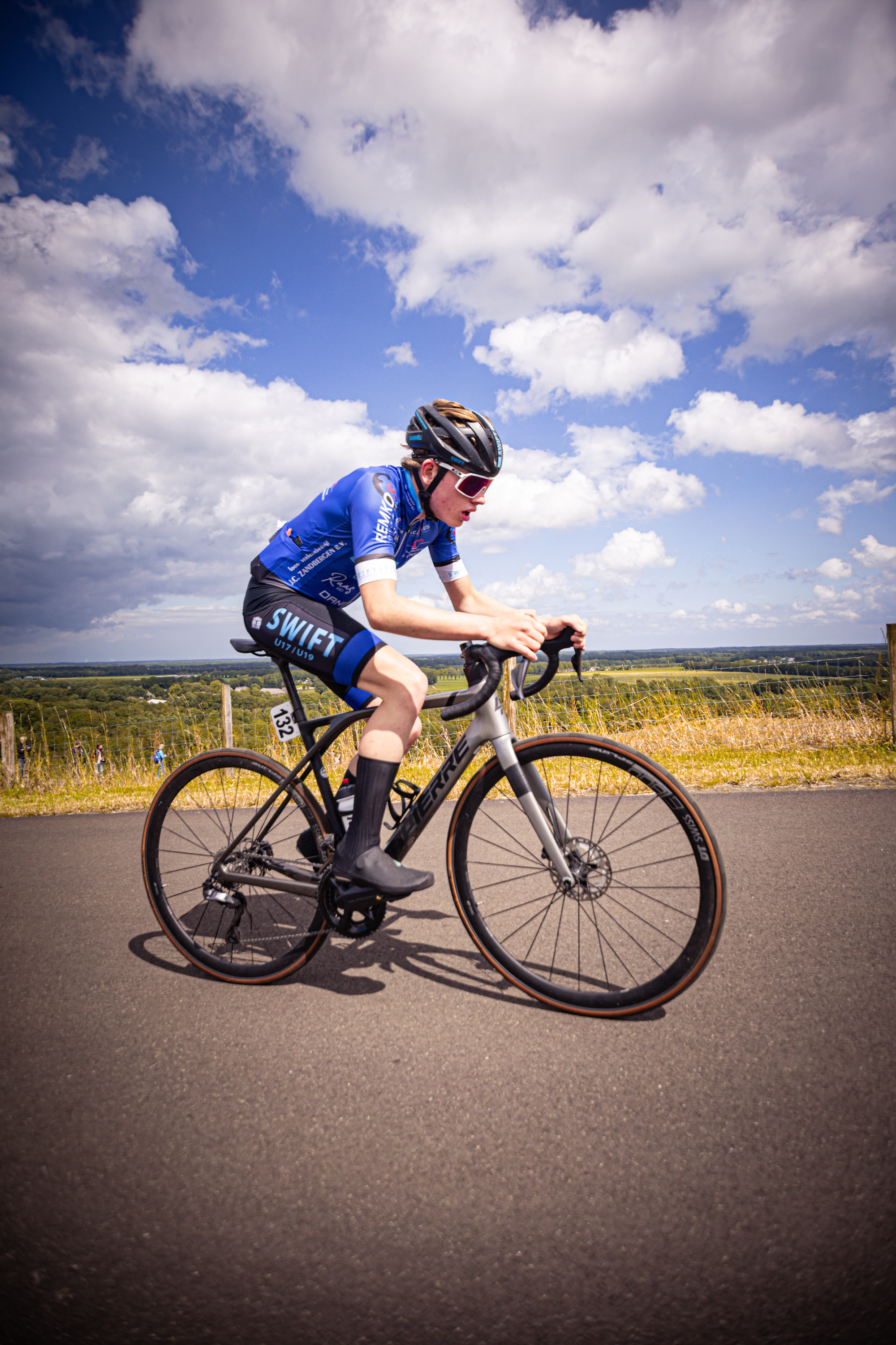 A person wearing a blue and white shirt is riding a bike on a road.