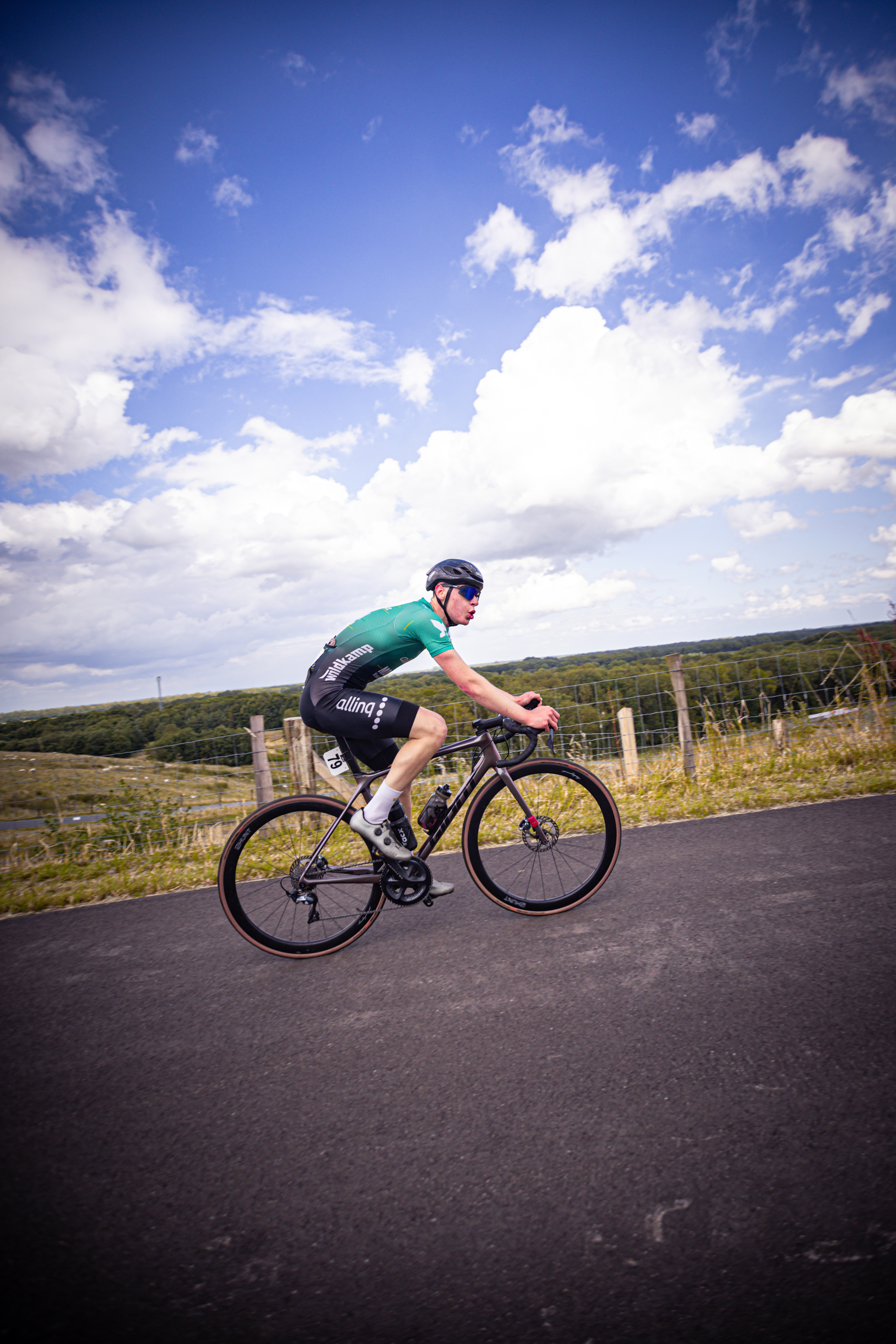 A man in a green shirt is riding a bike down a road.