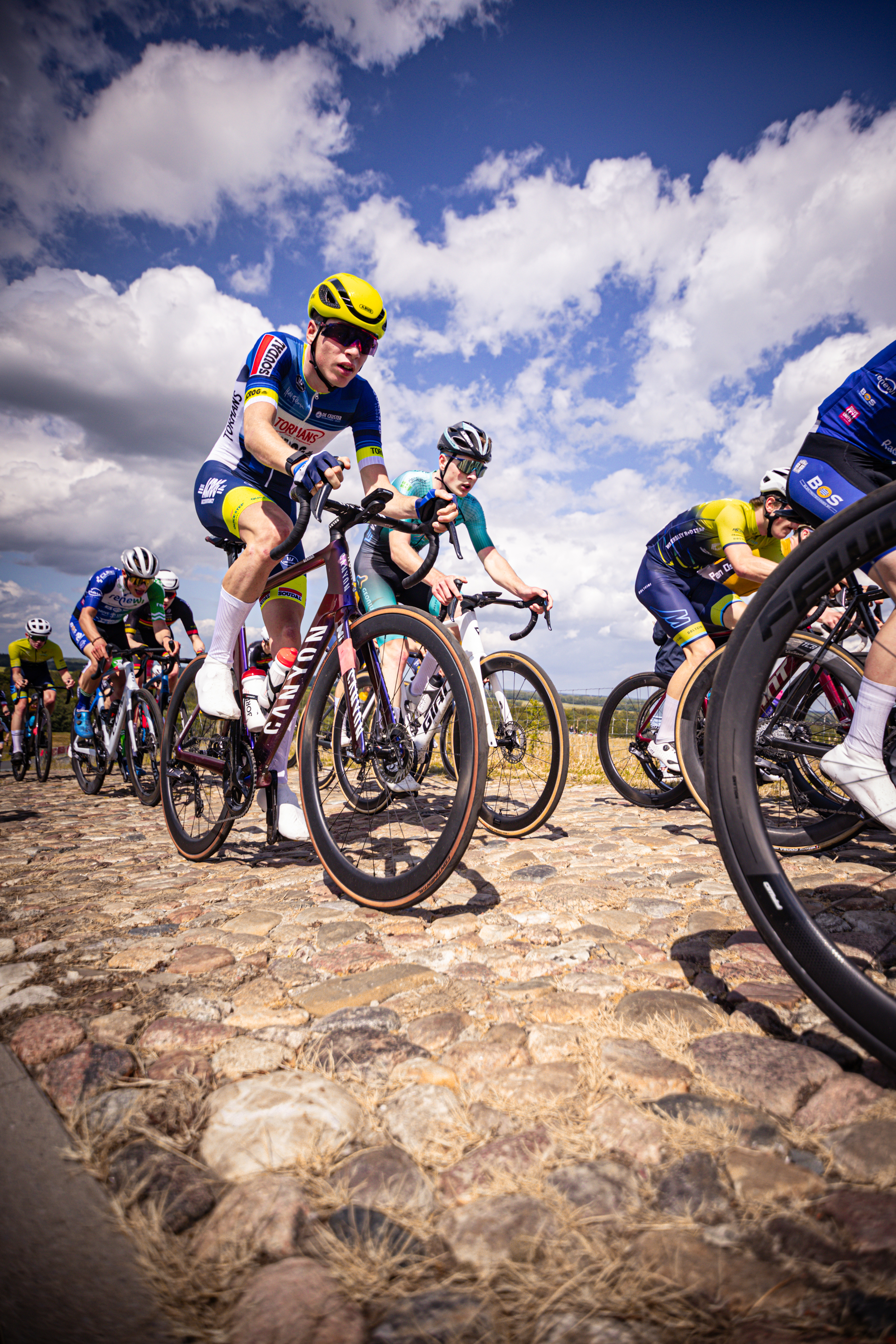 A young group of bikers wearing colorful racing gear participating in the Nederlands Kampioenschap.