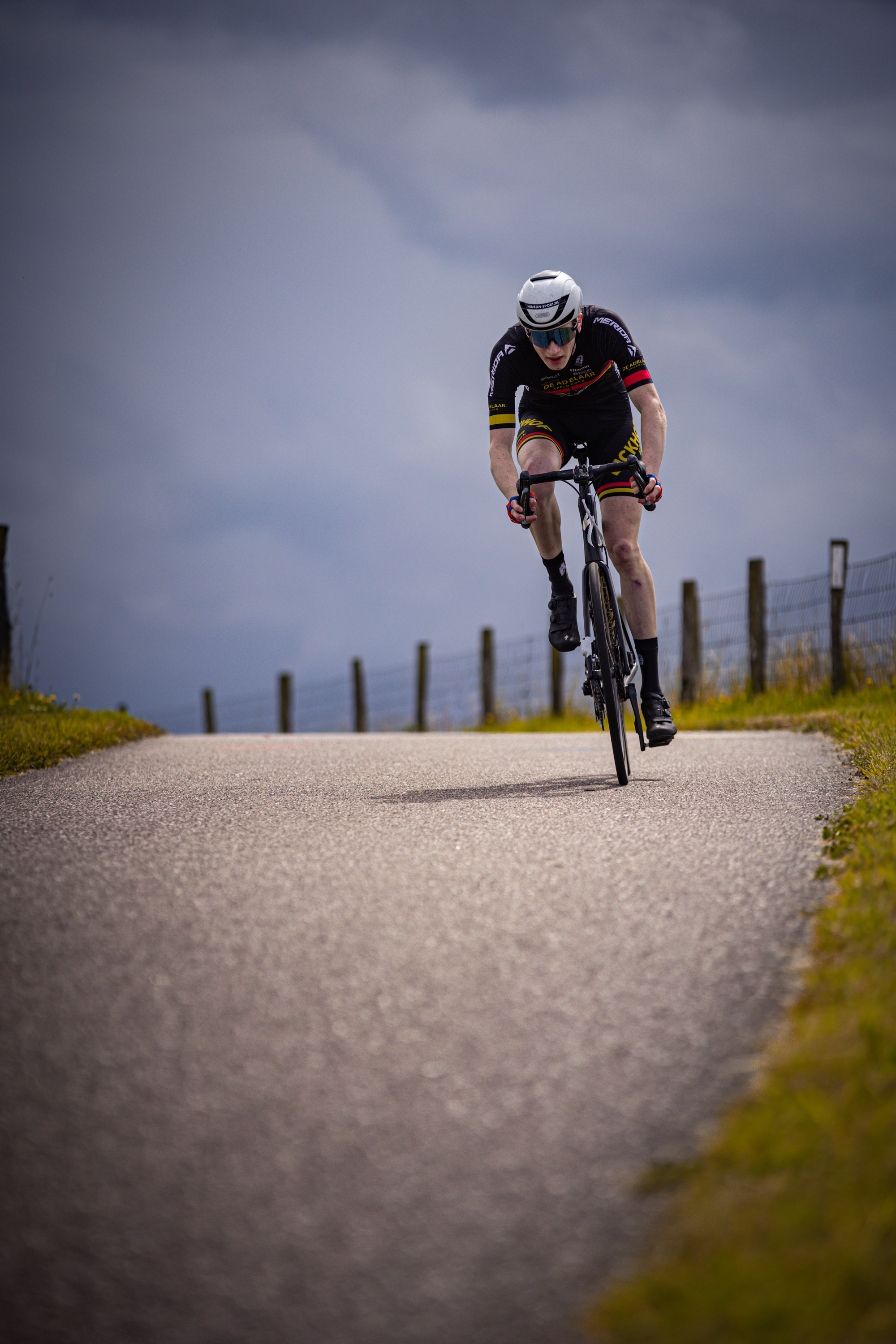 A man on a bicycle wearing black and yellow jersey.