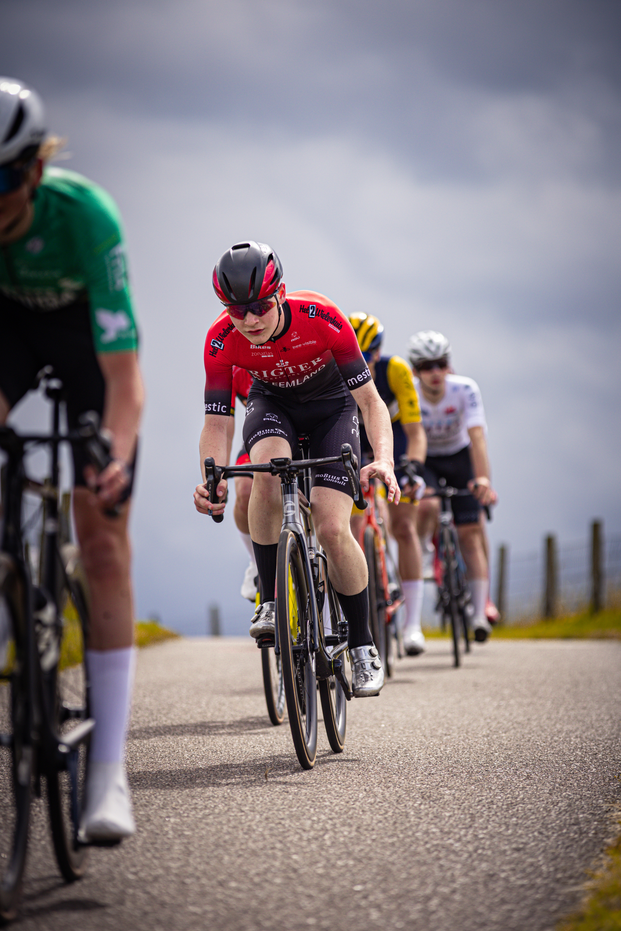 A group of bicycle racers are riding their bikes on the road.