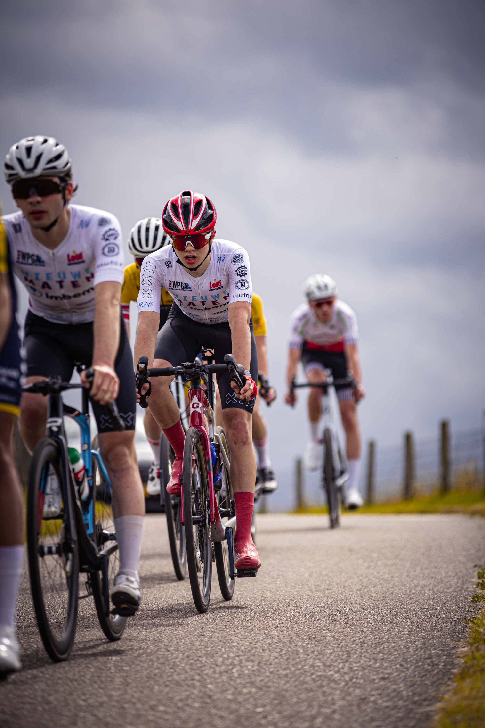 Three cyclists wearing white and red outfits on a track.