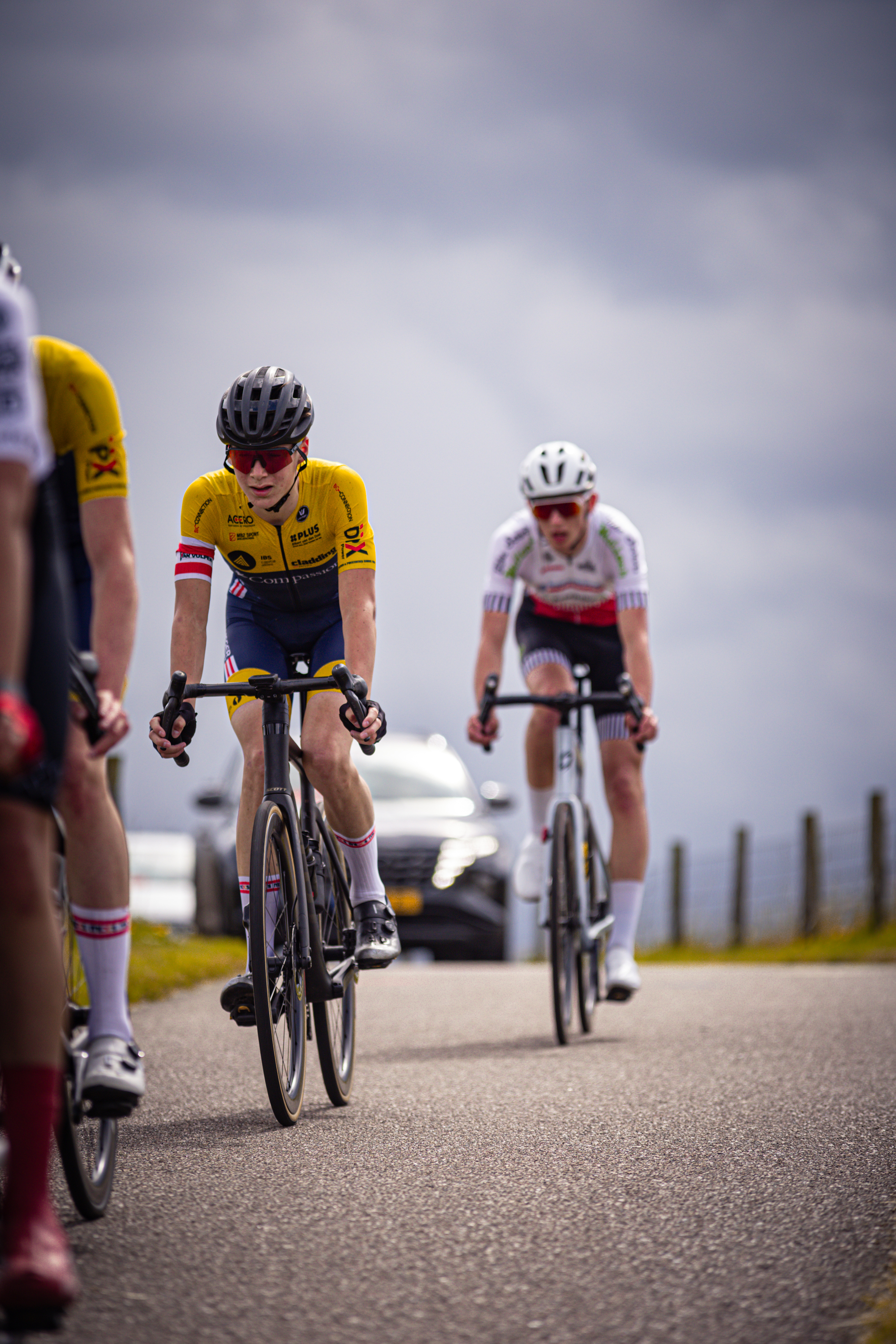 A group of cyclists race down a road during the Nederlands Kampioenschap.