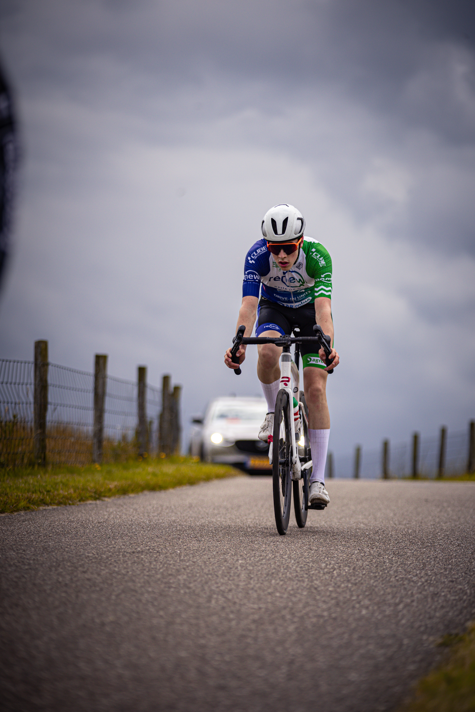 A bicyclist wearing a blue and white shirt with the number 10 on it races down a road.