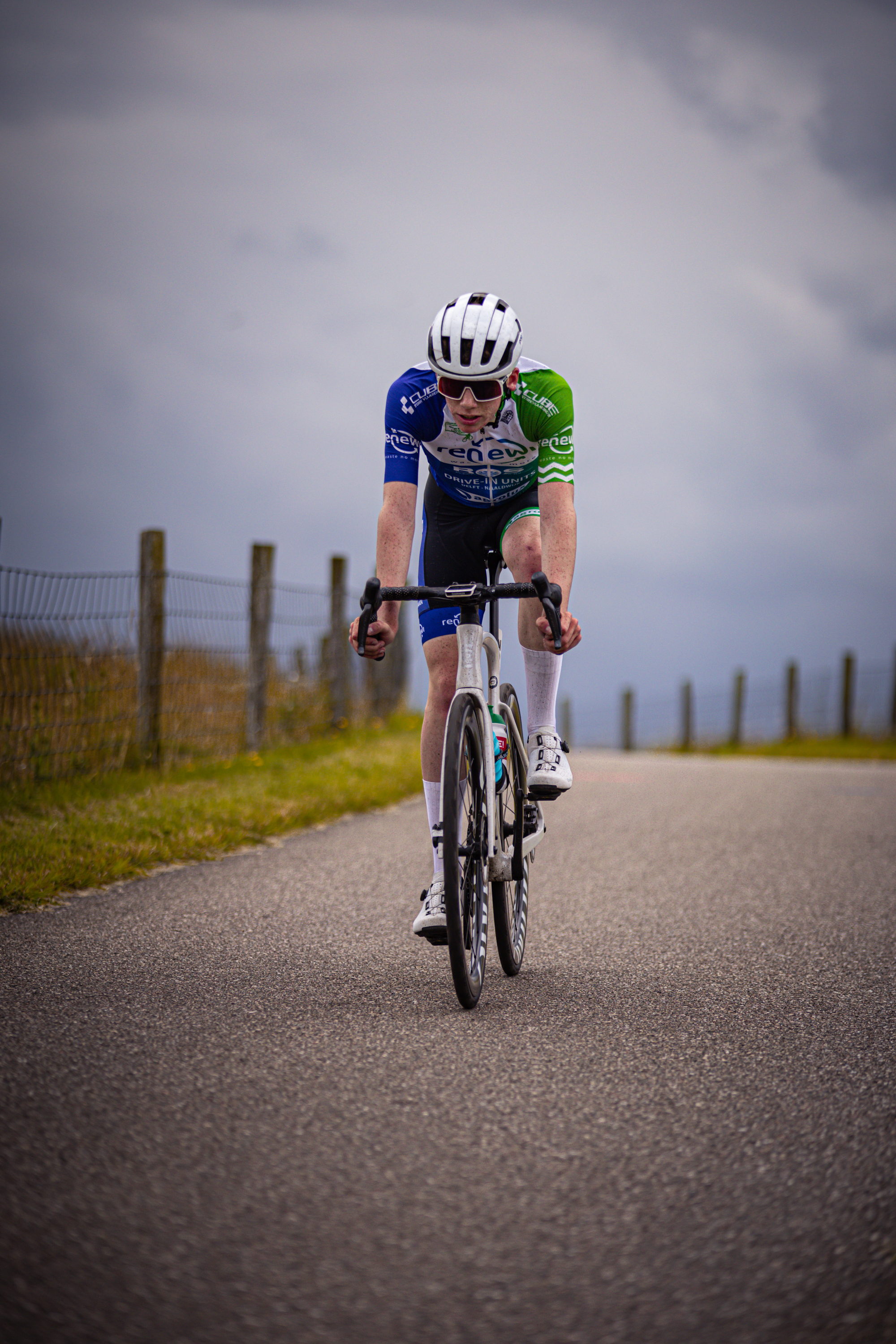 A man wearing a blue and white jersey is riding a bicycle.