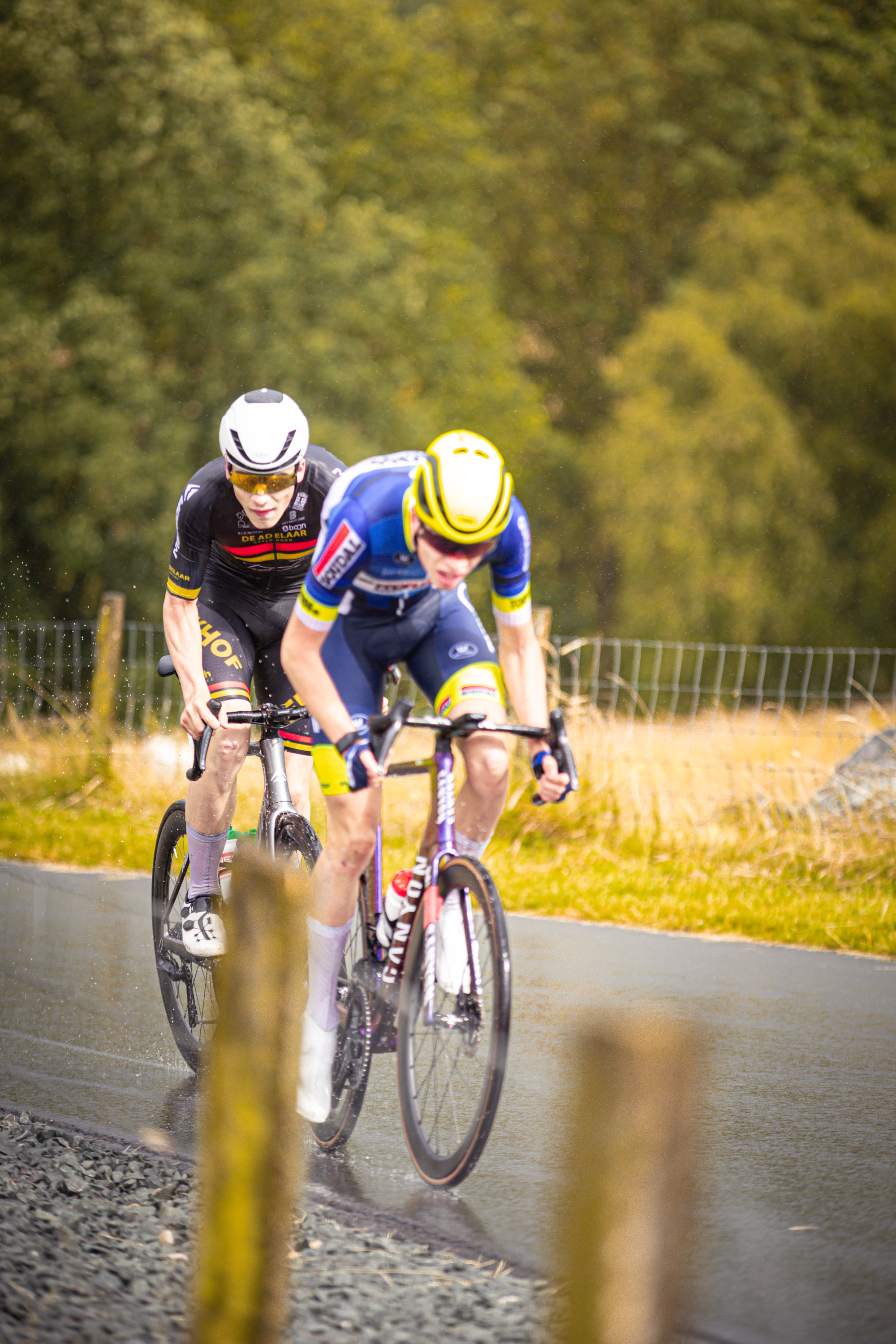 Two cyclists race on a track, one in blue and the other in black.