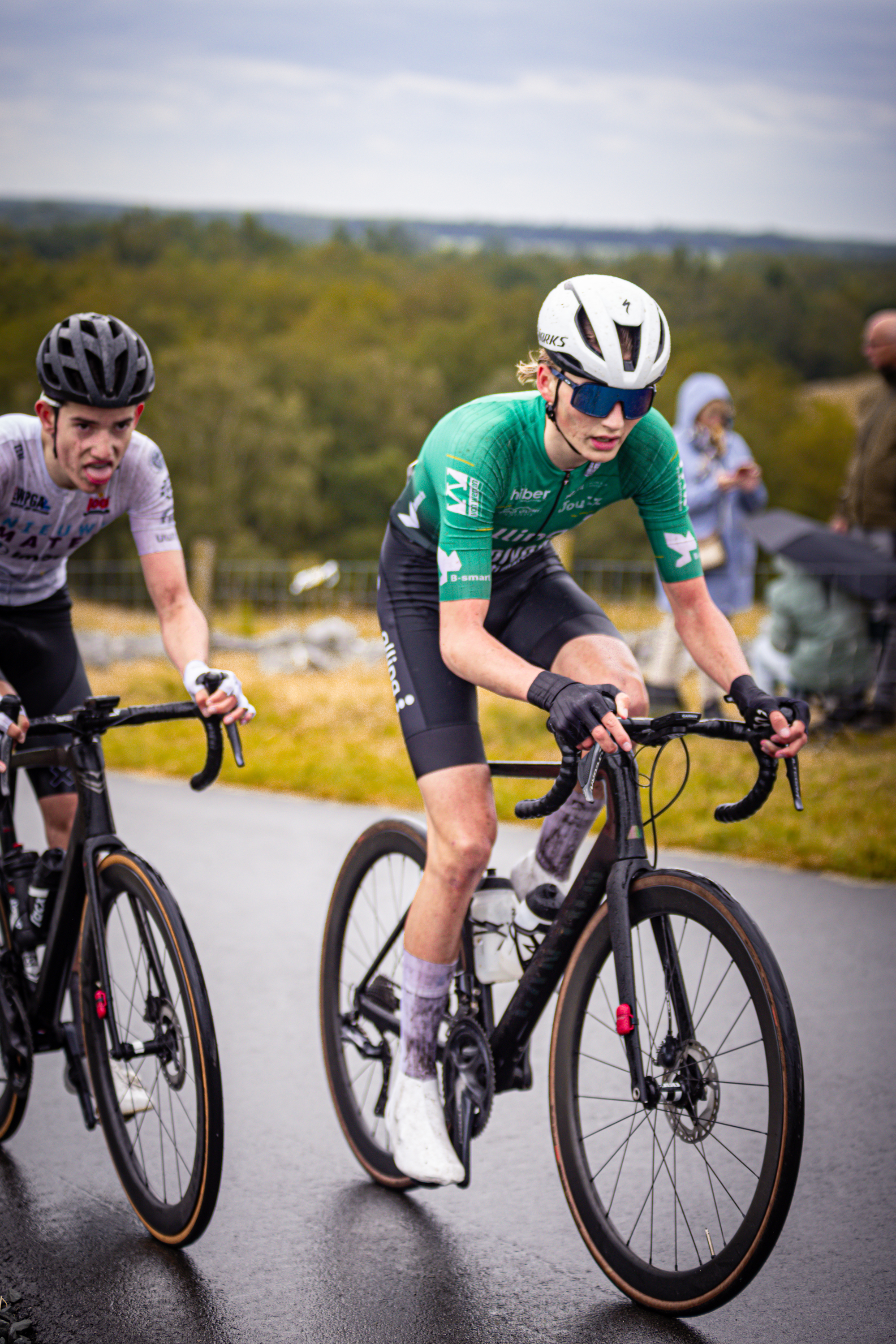 Two cyclists riding through a field and the word "Nederlands" appears in the scene.