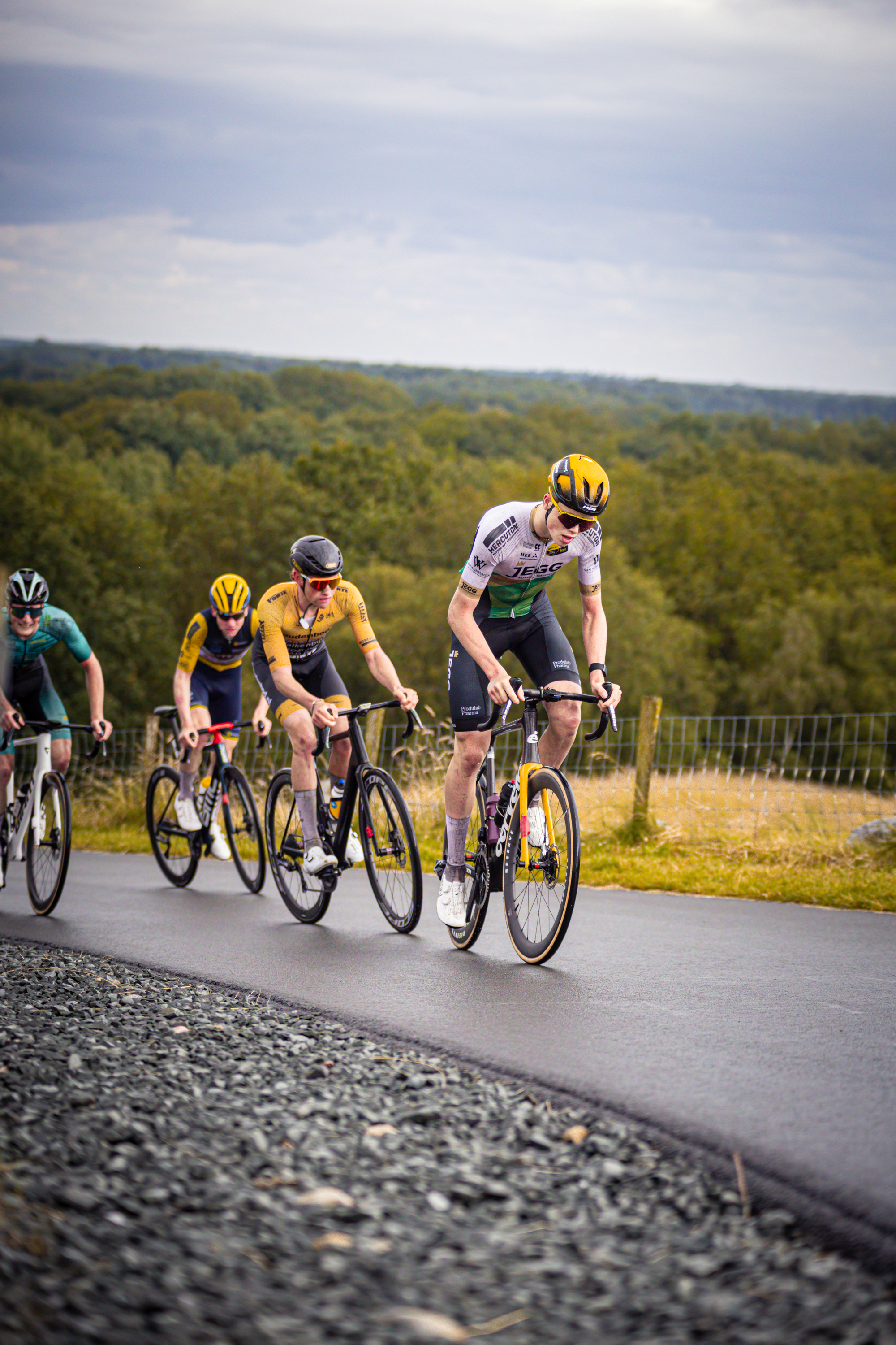 Four cyclists racing on a track, all wearing helmets.