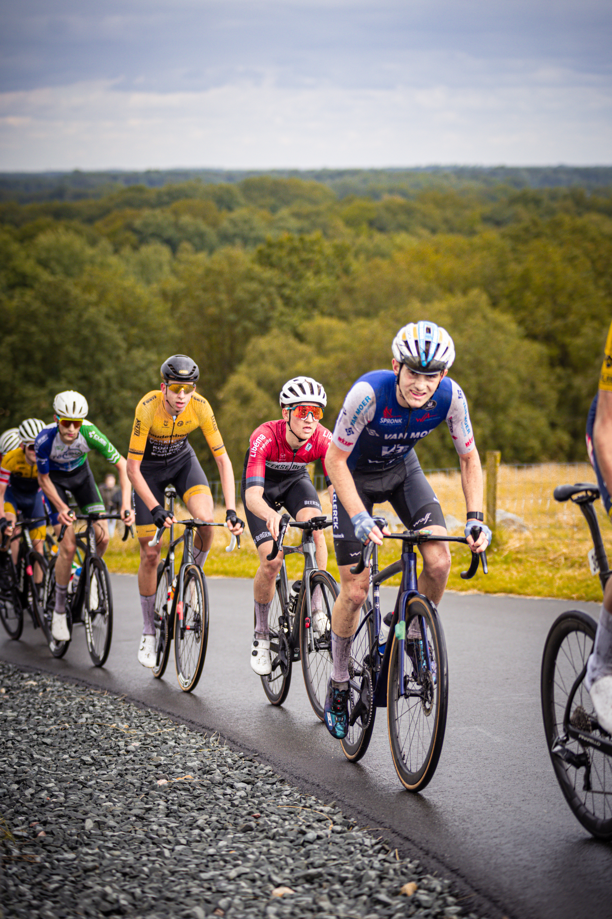 Four cyclists wearing helmets compete in the Nederlands Kampioenschap race.