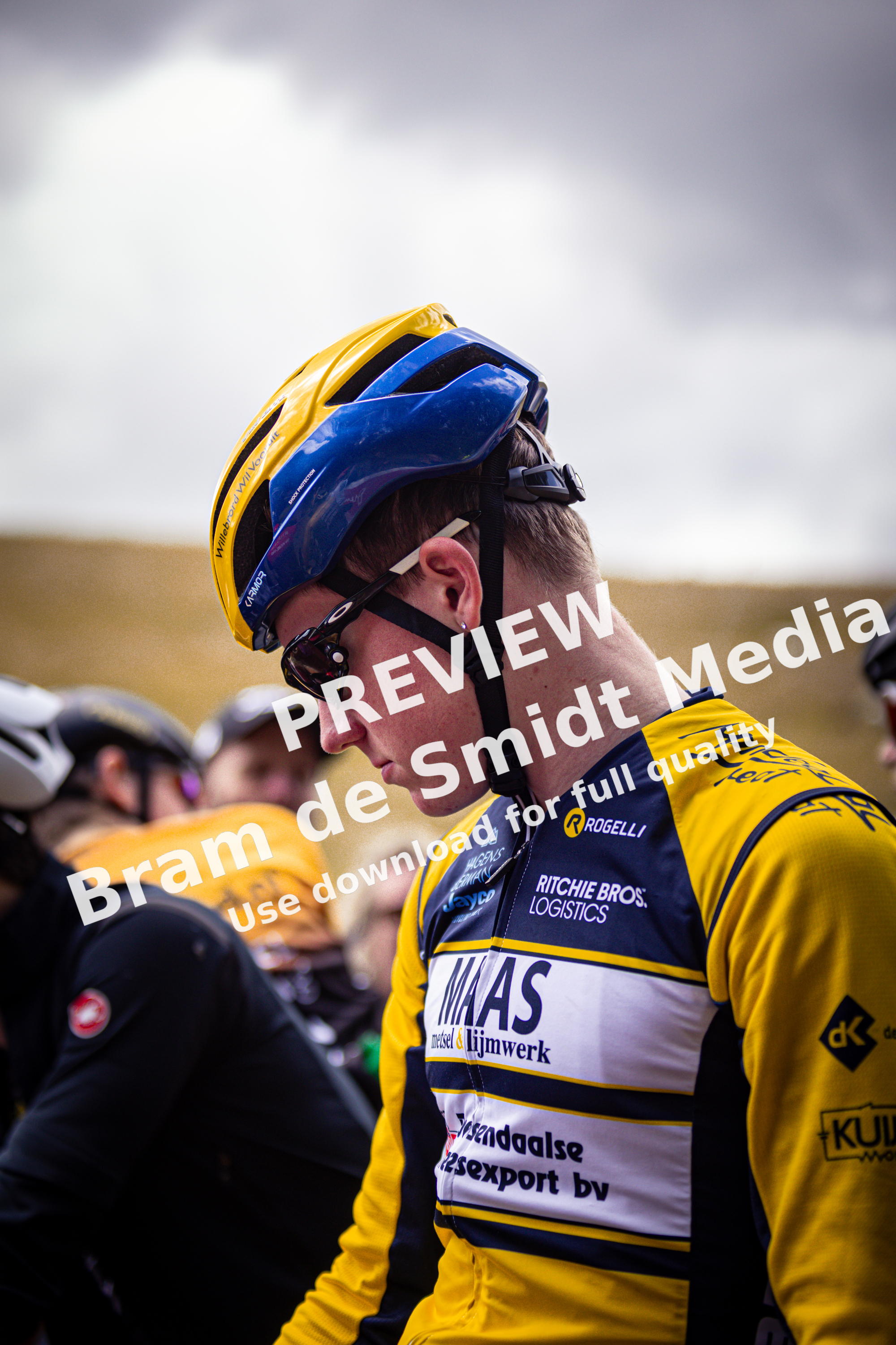 A young man in a cycling race wearing a blue helmet and a yellow and blue jersey.