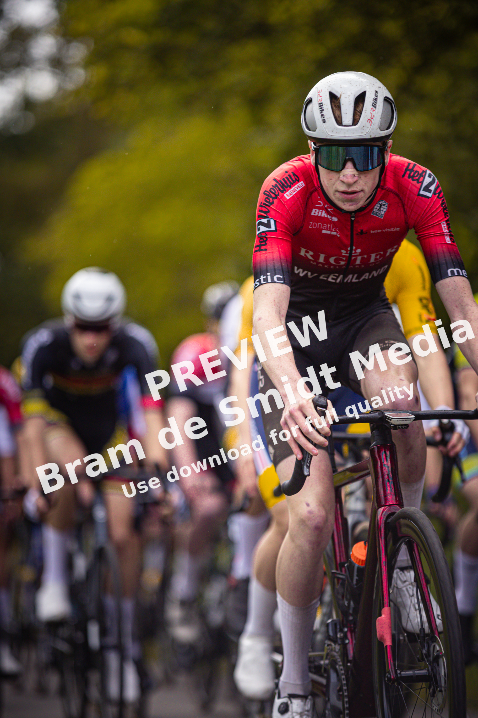 A male cyclist wearing a red and black jersey sponsored by Rikkia.