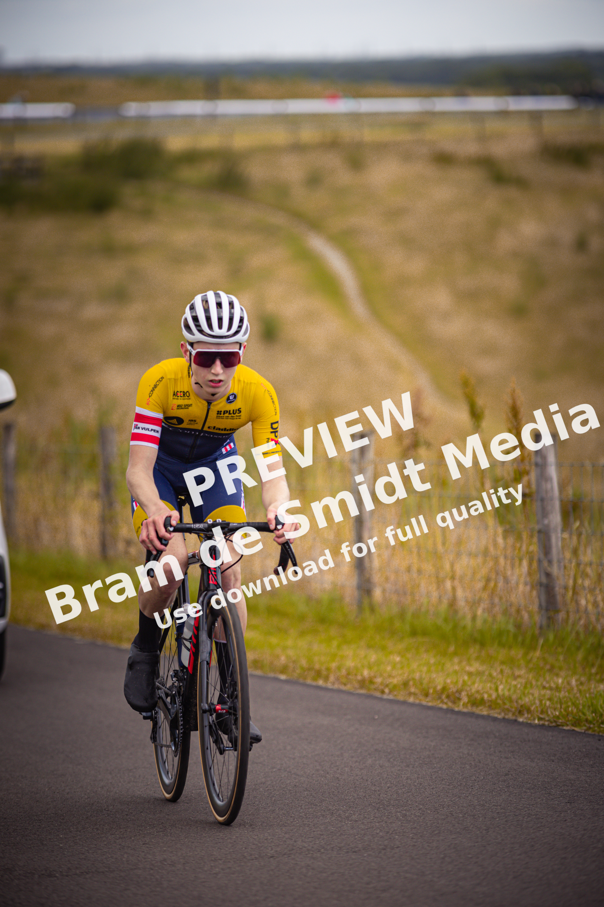 A person riding a bike wearing a yellow shirt and blue shorts.
